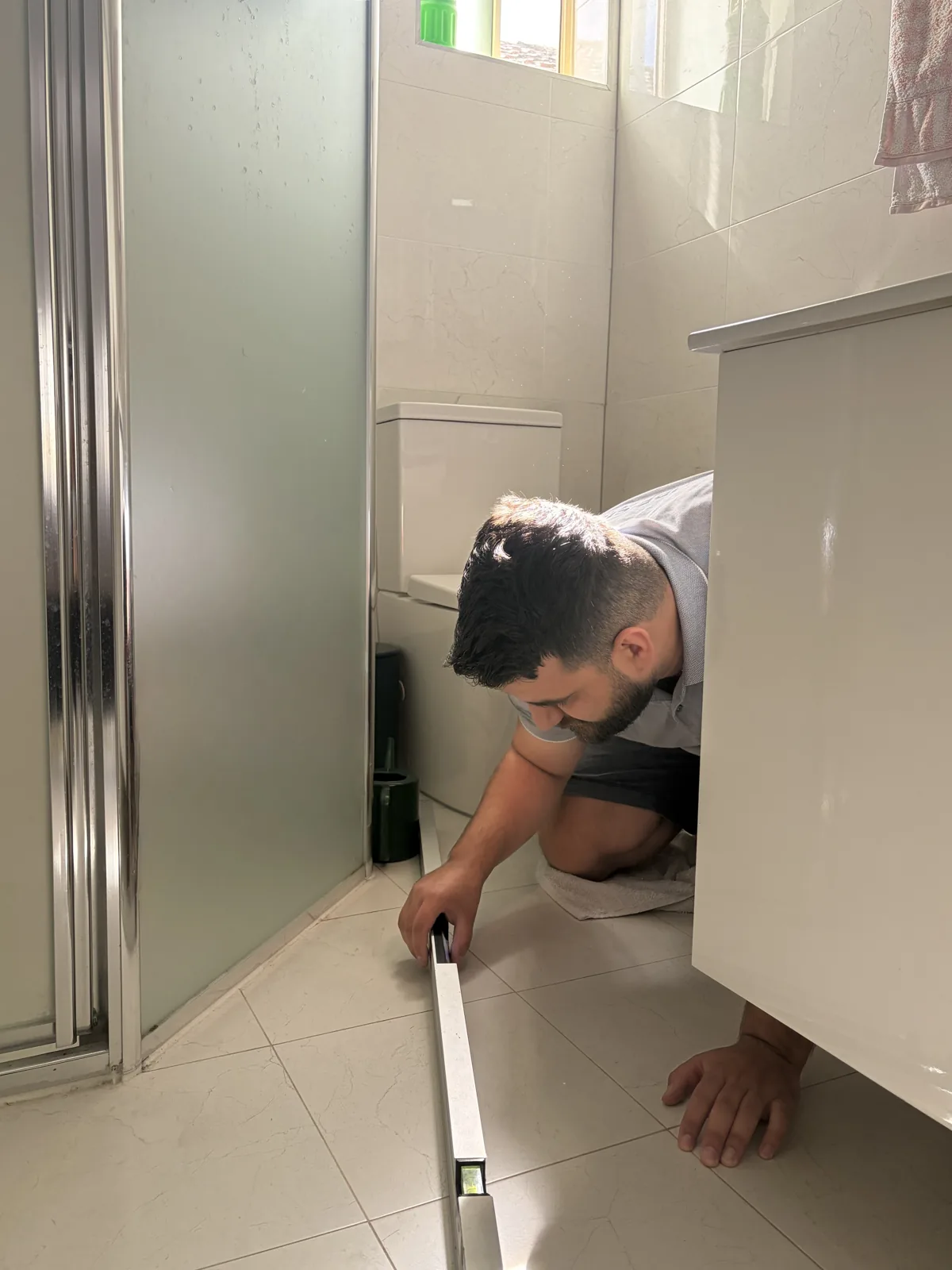 Ibrahim checking a tiled floor with a spirit level